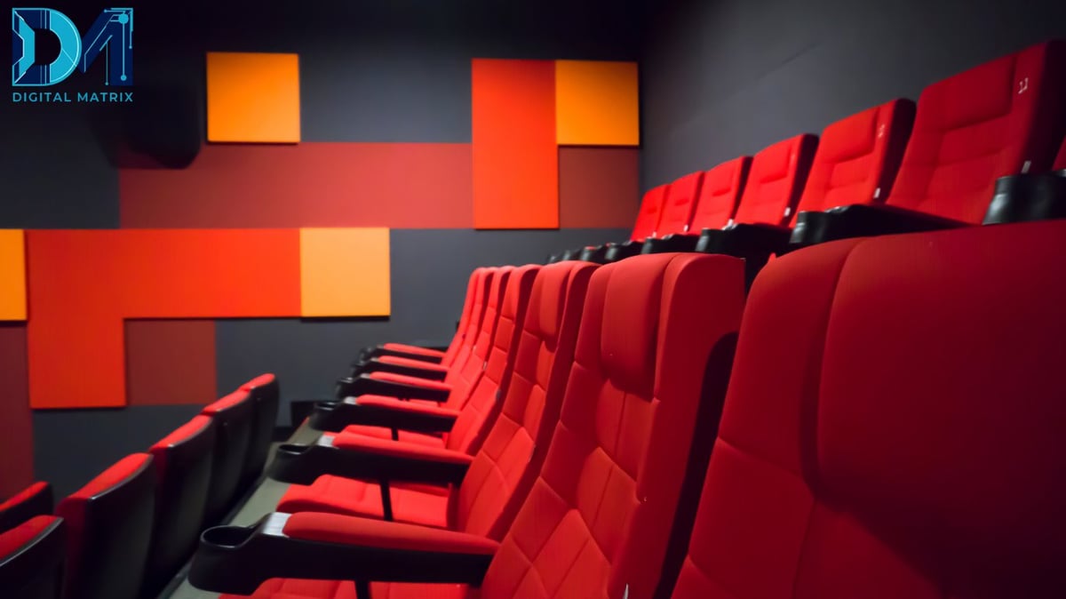 Modern movie theater with rows of red upholstered seats facing a dark wall with geometric orange and red panels